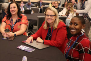 three school board members seated a table smiling into the camera