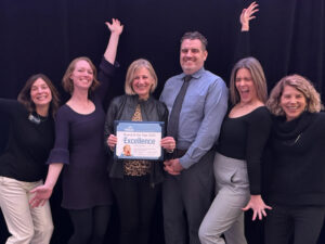 An award winning school board striking a celebratory pose with their superintendent 